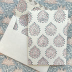Kaart met blockprint in roze en blauw, op een bijpassende envelop met een tafelkleed op de achtergrond