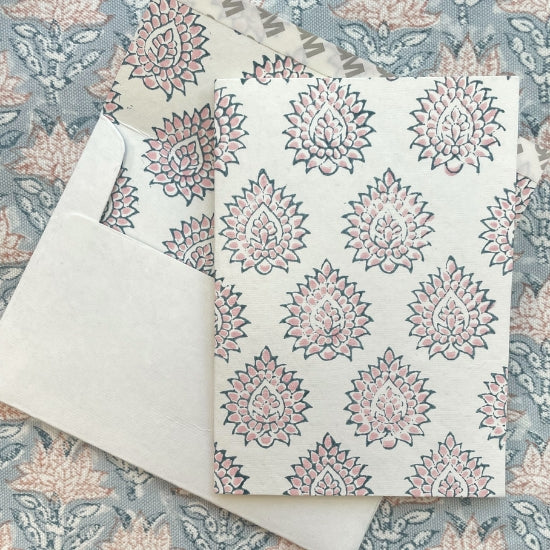 Kaart met blockprint in roze en blauw, op een bijpassende envelop met een tafelkleed op de achtergrond